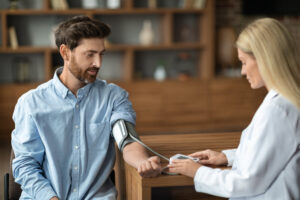 Doctora tomando la presión arterial a un hombre en un consultorio médico